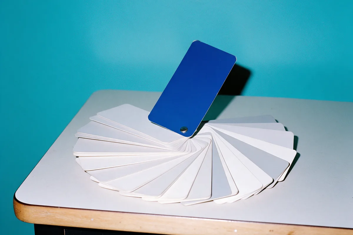 A fan of white color swatches with one blue card pulled out